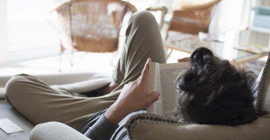A man reading a book on the couch.