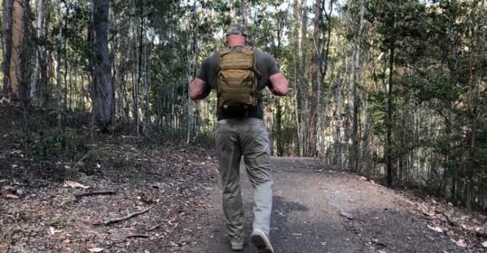 A man walking through the woods with a backpack, on a Podcast adventure.