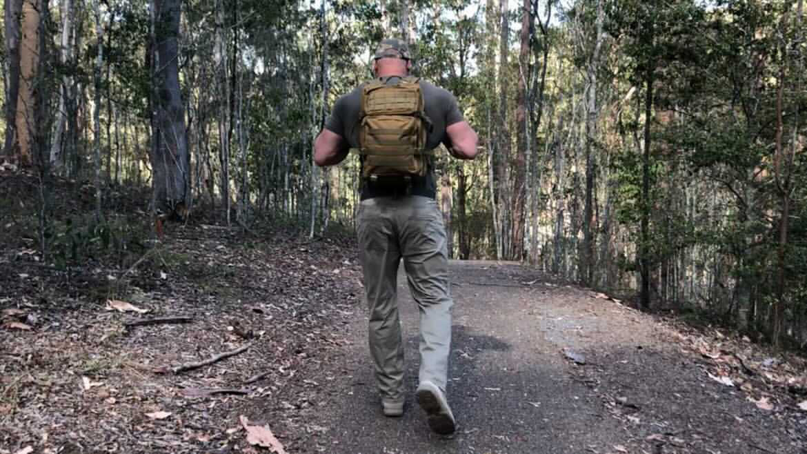 A man walking through the woods with a backpack, on a Podcast adventure.