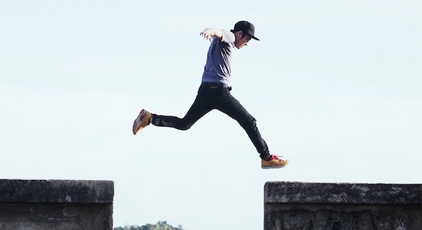 A man jumping over a concrete wall with purpose.