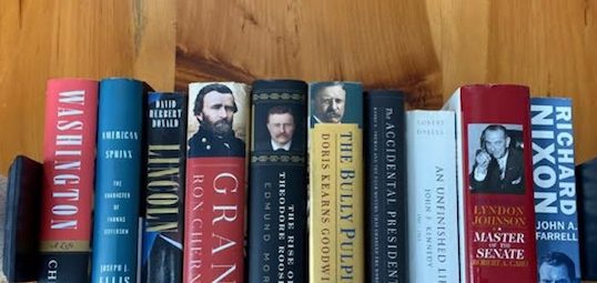 A stack of biographies on an American President, resting on a wooden table.