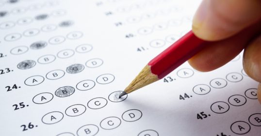 A person uses a pencil to decide on a test sheet.