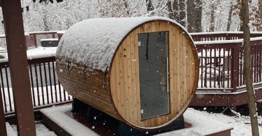A wooden sauna covered in snow on a deck creates a peaceful retreat for the mind.