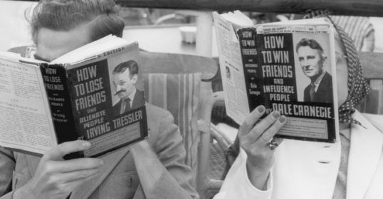 Two individuals on a bench reading books.