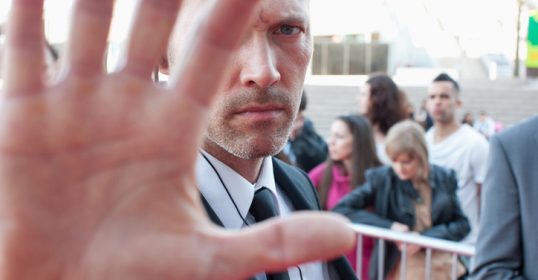 A man is making a stop sign with his hand, showcasing humanity.