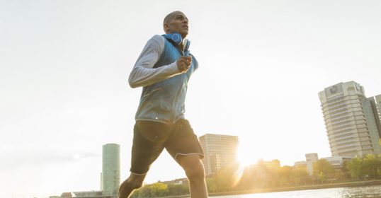 A man jogging near a river for his workout.