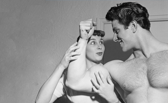 A black and white photo of a man and woman flexing their muscles.