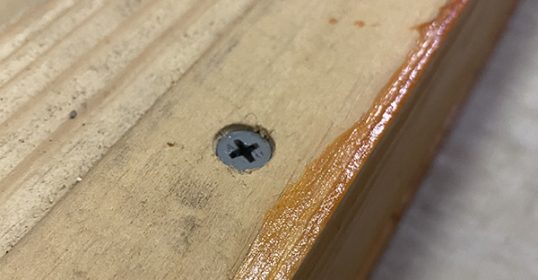 A close-up of a screw on a piece of wood with a countersink.