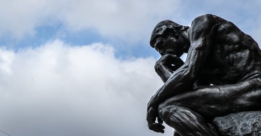 A statue of the thinker under a cloudy sky, showcasing hidden qualities.