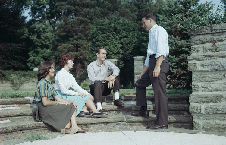 Four people sitting on steps in front of a building.