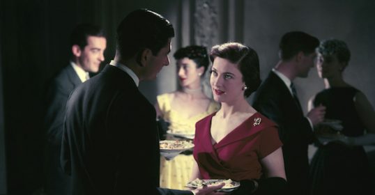 At Sunday Firesides, a woman in a red dress gracefully holds a plate of food.