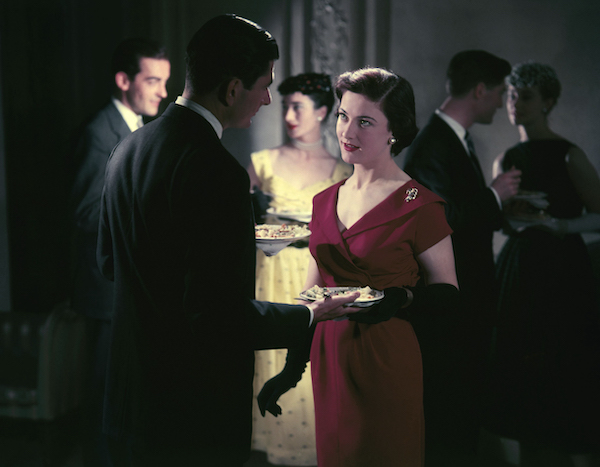 At Sunday Firesides, a woman in a red dress gracefully holds a plate of food.