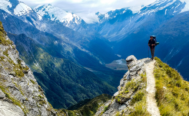 A person standing on the edge of a mountain in New Zealand, contemplating their path.