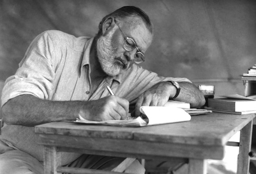 An author sitting at a table writing a book.