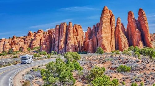 An RV embarking on the Ultimate Road Trip with red rock formations in the background.