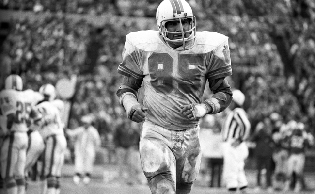A black and white photo of a football player running on the field during Sunday Firesides.