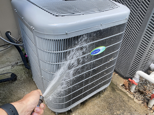 A person is spraying water on an air conditioner in the house.