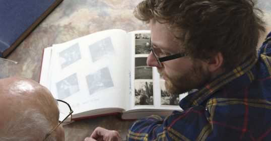 A man sitting at a table, deeply engrossed in a book.