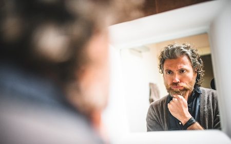 A man podcasting his self-reflection in front of the mirror.