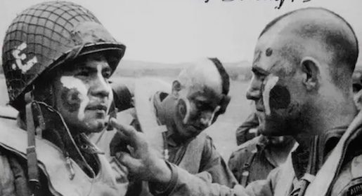 A black and white photo of two soldiers with paint on their faces during WWII.