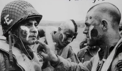A black and white photo of two soldiers with paint on their faces during WWII.