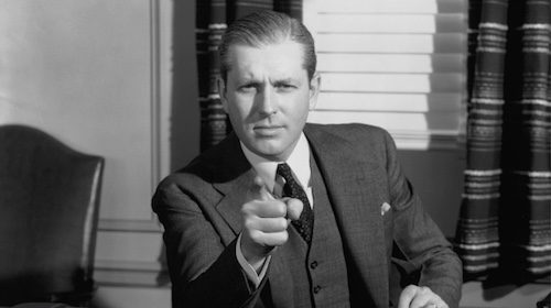 A man quickly pointing his finger at a desk.