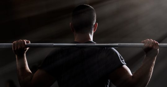 A man lifting a barbell on a bench in the gym, showcasing his strength.