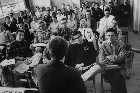 A black and white photo of a group of people in an education setting.