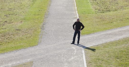A man standing on a path in a field, contemplating life's biggest decisions.
