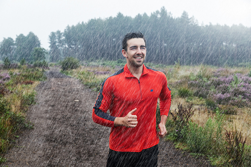 A man jogging in the rain for exercise.