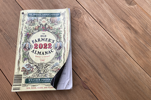 An old Farmer's Almanac rests on a wooden floor, praised for its wisdom.