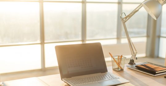A desk at work with a laptop and other items on it.