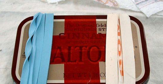An Altoids tin with blue and red ribbons, perfect for reuse.