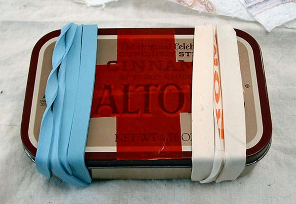 An Altoids tin with blue and red ribbons, perfect for reuse.