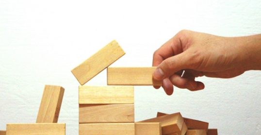 On a Sunday evening, a person is stacking wooden blocks to create a tower.