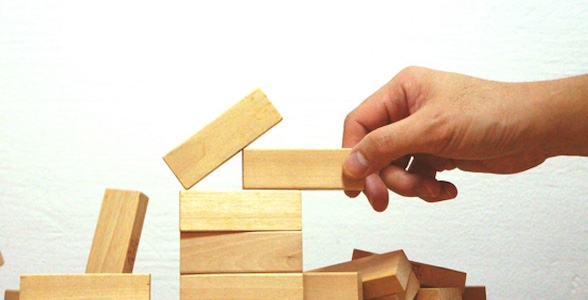 On a Sunday evening, a person is stacking wooden blocks to create a tower.