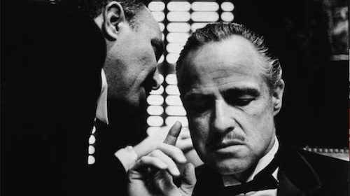 A black and white photo of two men in tuxedos, reminiscent of a scene from The Godfather.