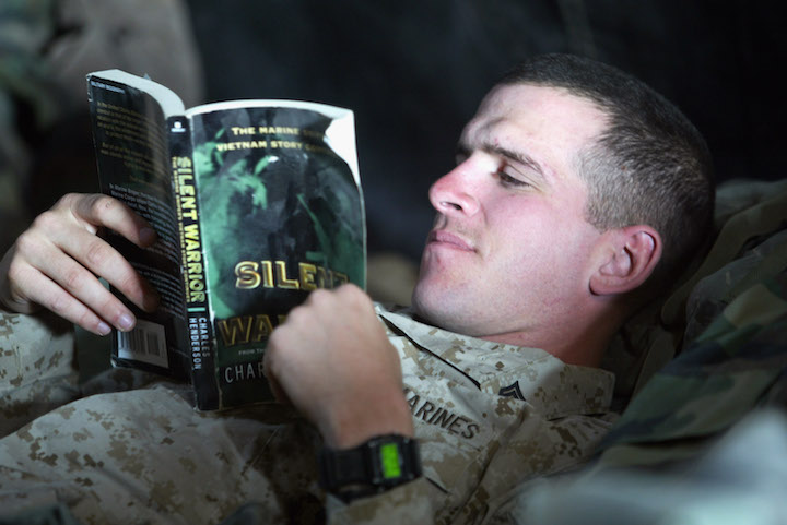 A man in a Marine Corps uniform reading a book from the Reading Lists.