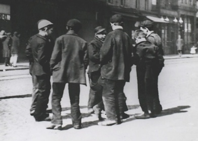 A group of men playing pitch-and-toss on a street.