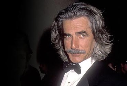 A man in a tuxedo with long hair and mustache.