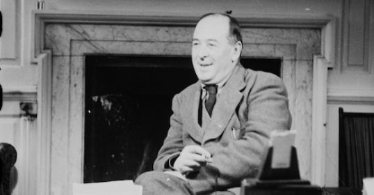 An old black and white photo of a man sitting at a C.S. Lewis desk.