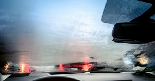 A car driving on a rainy day with the windshield fogging up.