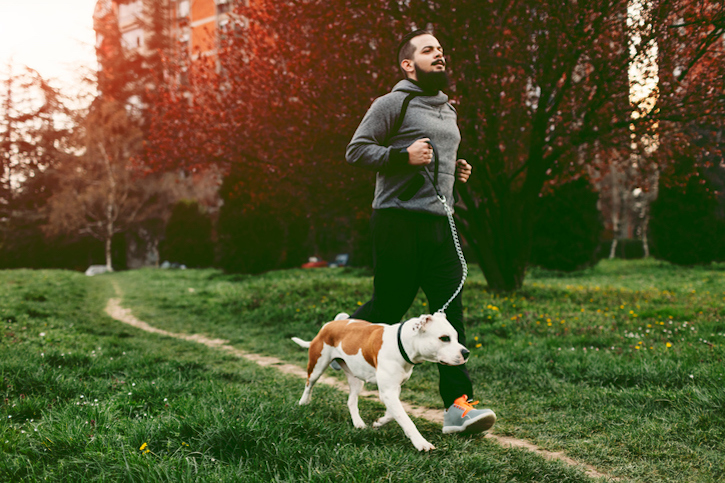 A man exercises with his dog in the park for weight management.