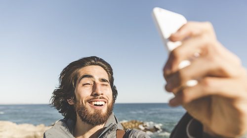 A man is taking a selfie on the beach.