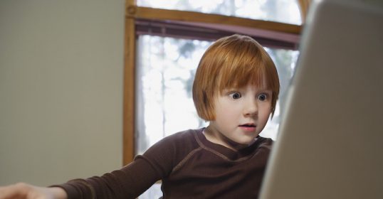 A young boy sits in front of the best laptop computer.