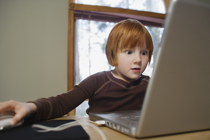 A young boy sits in front of the best laptop computer.