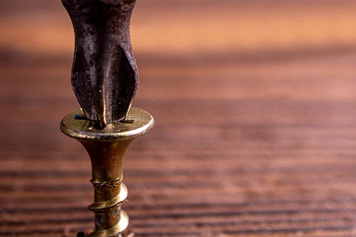 A brass screw on top of a wooden table prevents stripped screws.