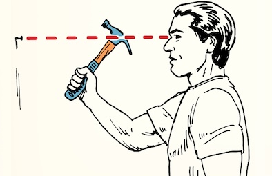 A person skillfully demonstrates how to handle a hammer, confidently holding it while staring straight ahead at a wall with a small nail. A red dotted line connects the nail and the person's focused eyes.