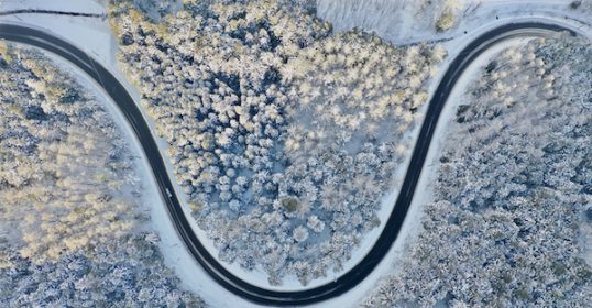 An aerial view of a U-shaped curve road in the snow.