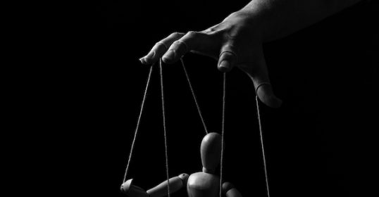 A black and white photo of a hand holding a puppet.